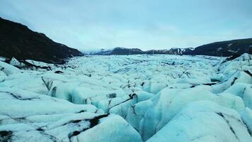 Aerial view of lake with ice rocks, vatnajokull glacier cap floating around frozen waters in iceland. Glacier lagoon forming ice landscape with icebergs and icy blocks, landmark. Slow motion. photo