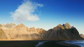 Drone shot of vestrahorn mountains in iceland, stokksnes beach peninsula creating majestic icelandic scenery. Beautiful nordic landscape with black sand beach, scenic route. Slow motion. photo