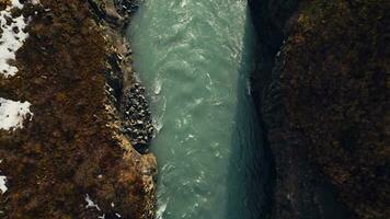 Aerial view of icelandic waterfall in river canyon, spectacular nordic scenery with water stream flowing between hills. Beautiful landscape in iceland with cliffs and fields. Slow motion. photo