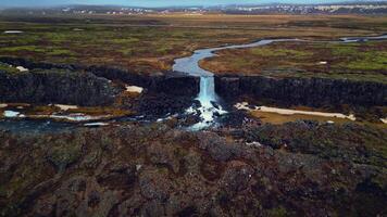 Aerial view of oxarafoss waterfall in iceland, spectacular huge water cascade falling down off cliffs. Icelandic landscape with river flowing from mountains. Slow motion. photo