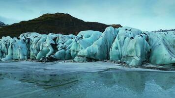 Drone shot of vatnajokull glacier caves, nordic massive ice rocks next to frozen water in icelandic scenery. Majestic icebergs crevasses in iceland. Close up. Slow motion. photo