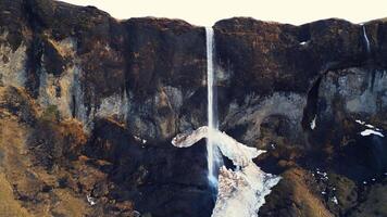 Aerial view of foss a sidu cascade in iceland running off of hills forming scandinavian landscape, nordic scenery. Beautiful icelandic waterfall flowing down snowy mountains. Slow motion. photo