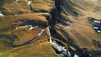 River course flowing among hills in iceland, natural foss a sidu waterfall in icelandic scenery. Spectacular cascade falling off from scandinavian cliffs. Slow motion. Drone shot. photo