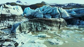 Aerial view of crevvase in iceland, huge ice blocks and dark caves on vatnajokull glacier cap. Diamond shaped icebergs and glacier lagoon creating nordic landscape with lake. Slow motion. photo