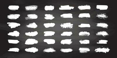 Grunge white brush strokes, paint roller elements on chalkboard background. Set of hand drawn vector  ink splash elements.