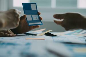 Close up ux developer and ui designer brainstorming about mobile app interface wireframe design on table with customer breif and color code at modern office.Creative digital development agency photo