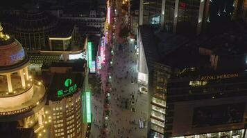 People at Nanjing Road at Night. Pedestrian Street in Huangpu District. Shanghai City, China. Aerial View. Drone Flies Downwards, Camera Tilts Up, Reveal Shot. video