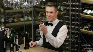 Confident and experienced sommelier at the wooden table with wine shelf in the background video