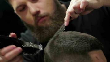 Men's hairstyling and haircutting with hair clipper in a barber shop or hair salon video