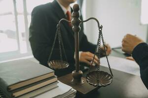 Business and lawyers discussing contract papers with brass scale on desk in office. Law, legal services, advice, justice and law concept picture with film grain effect photo