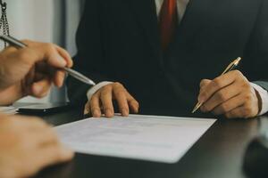 Business and lawyers discussing contract papers with brass scale on desk in office. Law, legal services, advice, justice and law concept picture with film grain effect photo