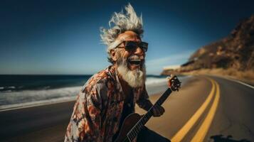 Hipster crazy senior man playing the guitar on the road highway on the beach side. photo