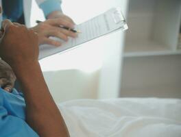 Close up of doctor sitting on bedside of male patient in hospital photo