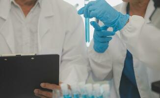 Health care researchers working in life science laboratory. Young female research scientist and senior male supervisor preparing and analyzing microscope slides in research lab. photo