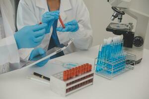 Health care researchers working in life science laboratory. Young female research scientist and senior male supervisor preparing and analyzing microscope slides in research lab. photo