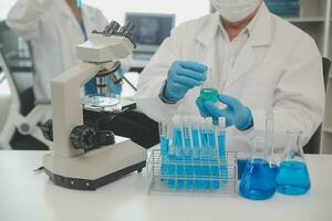 Health care researchers working in life science laboratory. Young female research scientist and senior male supervisor preparing and analyzing microscope slides in research lab. photo