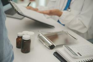 Doctor and patient sitting and talking at medical examination at hospital office, close-up. Therapist filling up medication history records. Medicine and healthcare concept. photo