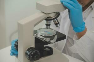 Health care researchers working in life science laboratory. Young female research scientist and senior male supervisor preparing and analyzing microscope slides in research lab. photo