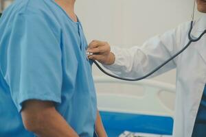 Close up of Female Doctor using stethoscope putting beat heart diagnose with patient in examination room at a hospital, check-up body, Medical and Health Care Concept. photo