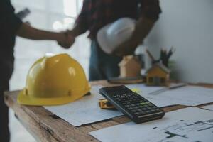 Close up of civil male engineer asian working on blueprint architectural project at construction site at desk in office. photo