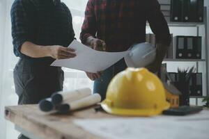 Close up of civil male engineer asian working on blueprint architectural project at construction site at desk in office. photo