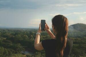 Young woman traveler in casual clothes with backpack from back on background of beautiful view on mountains photo