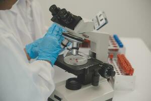 Health care researchers working in life science laboratory. Young female research scientist and senior male supervisor preparing and analyzing microscope slides in research lab. photo