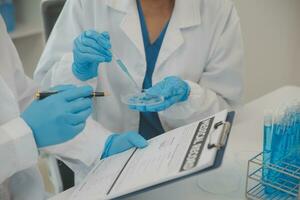 Health care researchers working in life science laboratory. Young female research scientist and senior male supervisor preparing and analyzing microscope slides in research lab. photo