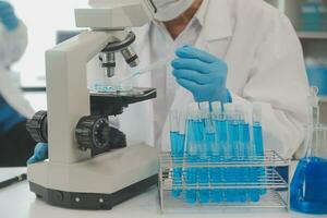 investigadores de atención médica que trabajan en el laboratorio de ciencias de la vida. joven científica investigadora y supervisora masculina senior preparando y analizando portaobjetos de microscopio en el laboratorio de investigación. foto