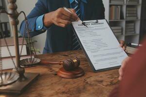 Justice and Law concept. Legal counsel presents to the client a signed contract with gavel and legal law or legal having team meeting at law firm in background photo