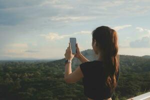 Young woman traveler in casual clothes with backpack from back on background of beautiful view on mountains photo