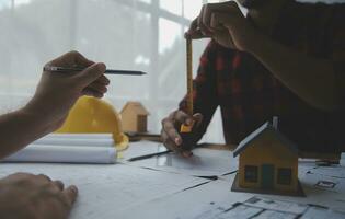 Close up of civil male engineer asian working on blueprint architectural project at construction site at desk in office. photo