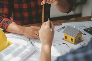 Close up of civil male engineer asian working on blueprint architectural project at construction site at desk in office. photo