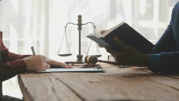 Justice and Law concept. Legal counsel presents to the client a signed contract with gavel and legal law or legal having team meeting at law firm in background photo