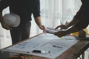 Close up of civil male engineer asian working on blueprint architectural project at construction site at desk in office. photo