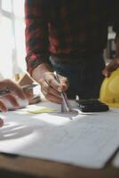Close up of civil male engineer asian working on blueprint architectural project at construction site at desk in office. photo