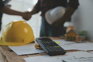 Close up of civil male engineer asian working on blueprint architectural project at construction site at desk in office. photo