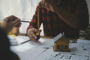 Close up of civil male engineer asian working on blueprint architectural project at construction site at desk in office. photo