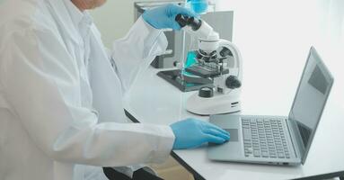 Health care researchers working in life science laboratory. Young female research scientist and senior male supervisor preparing and analyzing microscope slides in research lab. photo