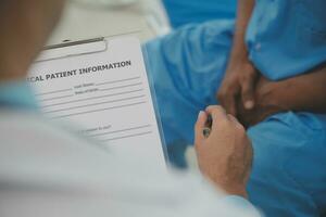 Close up of doctor sitting on bedside of male patient in hospital photo