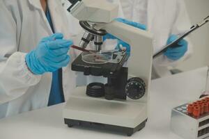 investigadores de atención médica que trabajan en el laboratorio de ciencias de la vida. joven científica investigadora y supervisora masculina senior preparando y analizando portaobjetos de microscopio en el laboratorio de investigación. foto