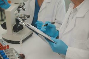 investigadores de atención médica que trabajan en el laboratorio de ciencias de la vida. joven científica investigadora y supervisora masculina senior preparando y analizando portaobjetos de microscopio en el laboratorio de investigación. foto