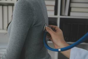 Asian doctor woman visited patient woman to diagnosis and check up health at home or private hospital. Female patient explain health problem and symptoms to doctor .Health care premium service at home photo