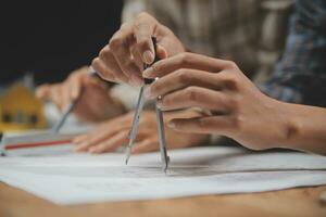 Team of multiethnic architects working on construction plans in meeting room. Engineers discussing on project in office. Mature businessman and woman standing around table working on blueprint. photo