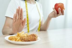 slim female body confuse French fries and fried chicken. Woman in restaurant achieves weight loss goal for healthy life, crazy about thinness, thin waist, nutritionist. Diet, body shape. photo