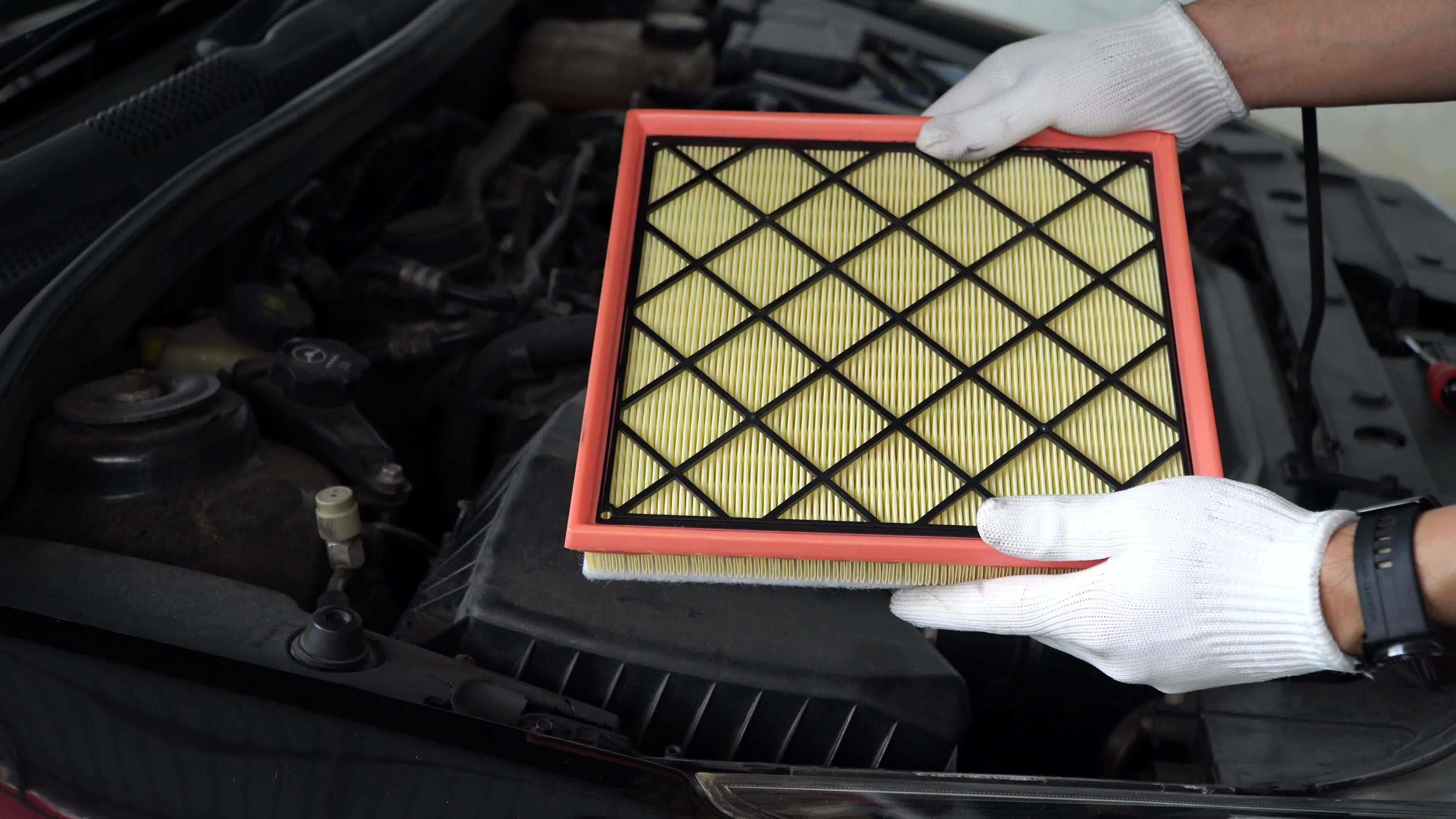 New air filter of car held by auto mechanic with engine.Car maintenance