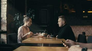 un hombre y un mujer son sentado en un café y hablando terminado un taza de té. relajado conversacion en un agradable ambiente video