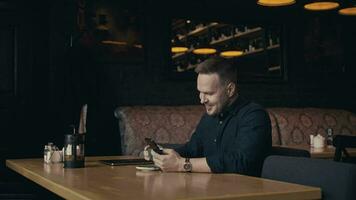 A man sits in a stylish cafe and uses a smartphone. Constant communication is possible thanks to the Internet. video