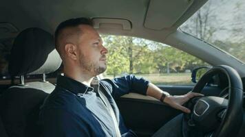 un adulto y grave hombre es conducción un coche. el conductor es enfocado en el la carretera y controlador el coche. video