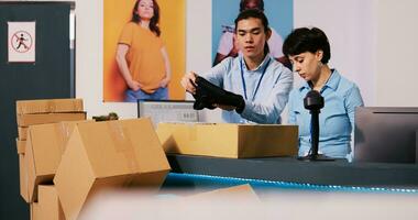 Diverse workers discussing shipping details in modern boutique, preparing packages for delivery. Employees working at customers orders, putting fashionable clothes in carton boxes in shopping centre photo